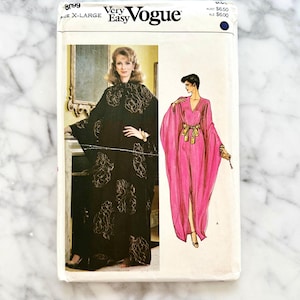 Könnte beinhalten: Ein Vintage Very Easy Vogue Schnittmuster. Die Schnittmusterhülle zeigt Illustrationen von zwei verschiedenen Kleidern. Die Hülle ist weiß mit schwarzem Text und einem blauen Punkt. Die Mustergröße ist X-Large.