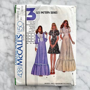 Könnte beinhalten: Eine McCall's 4381 Schnittmusterhülle für ein Kleid in Misses- und Junior-Petite-Größen. Das Cover zeigt Illustrationen von drei Kleider-Varianten: ein langes violettes Kleid, ein kurzes Blumenkleid und ein langes cremefarbenes Kleid mit Spitze.