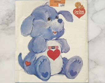 Könnte beinhalten: Ein Vintage-Nähmuster für ein blaues Care Bear Cousin Plüschtier in Form eines Hundes. Das Muster trägt den Titel "Loyal Heart Dog" und enthält ein Bild des fertigen Plüschtiers. Das Muster stammt von Butterick und hat die Nummer 3371.