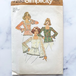 May include: Vintage Simplicity sewing pattern number 1233 for a blouse with a 32 1/2 inch bust. The pattern includes three different styles of blouses with bell sleeves and a tie at the waist. The pattern is printed on a white background with brown text.
