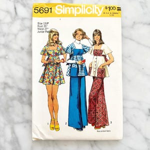 May include: Simplicity sewing pattern number 5691 for junior petite sizes. The pattern includes three different styles: a floral print dress, a gingham print top and trousers, and a red and white patterned top and trousers. The pattern is for sizes 13JP and includes instructions for bias printed fabric.