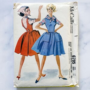 May include: Vintage McCall's sewing pattern featuring illustrations of two women in dresses. The pattern includes instructions for a dress, blouse, and scarf. The cover is aged, with the text "MISSES' AND JUNIOR DRESS, BLOUSE AND SCARF".