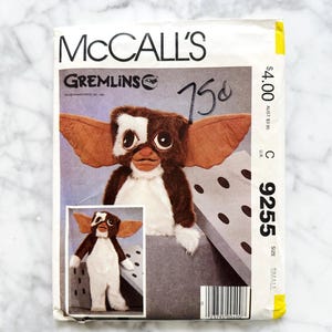 May include: A vintage McCall's sewing pattern featuring a Gremlins character. The pattern cover displays a plush Gremlin with brown, white, and tan fur, large ears, and the text "GREMLINS". The price is marked as 75¢.