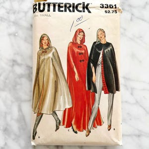May include: Vintage sewing pattern envelope for a hooded cape. The pattern is by Butterick and the pattern number is 3361. The envelope shows three different styles of capes: one in beige, one in red, and one in black.
