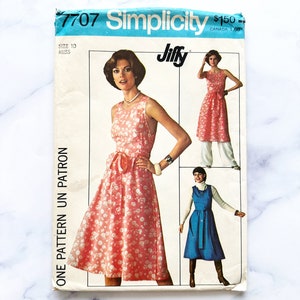 May include: Vintage Simplicity sewing pattern 7707 for a Jiffy dress. The pattern is for size 10 miss and includes instructions for three different styles of dresses. The pattern cover features a model wearing a pink floral dress with a bow.