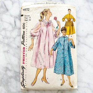 May include: Vintage Simplicity pattern 4972 for Misses size 14, bust 32. The pattern envelope features illustrations of three different robes in pink, yellow, and blue. The envelope is printed with the Simplicity logo and pattern details.