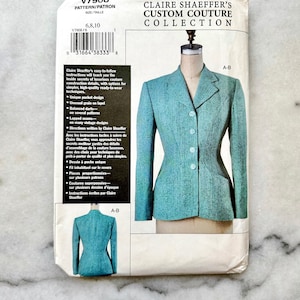 May include: A vintage sewing pattern for a Claire Shaeffer custom couture jacket. The pattern packet features a teal jacket on a mannequin, with a smaller image of the jacket's back. Text includes pattern number, size, and design details.