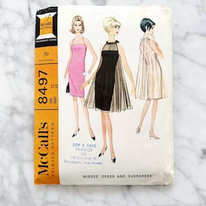May include: Vintage McCall's sewing pattern for a misses' dress and overdress. The pattern number is 8497 and the size is 12, bust 32. The pattern is for a dress with a sleeveless, scoop neck bodice and a skirt that falls to the knee. The overdress is a sheer, sleeveless, halter-style top with a high neckline.