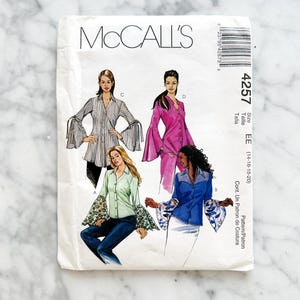 May include: A vintage McCall's sewing pattern packet featuring illustrations of women's blouses with flared sleeves. The packet is white with the brand name and pattern number 4257. The size range is EE (14-16-18-20).