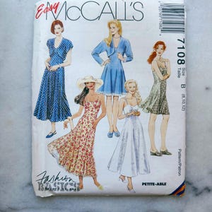 May include: A white McCall's sewing pattern envelope, number 7108, size B (8, 10, 12). The front features illustrations of five different dress styles, including floral and polka dot prints, with the text Easy McCall's, Fashion Basics, and Petite-Able.