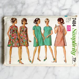 May include: Vintage Simplicity sewing pattern 7484 for a dress. The pattern is for misses sizes 12, 14, 16, and 18. The pattern features five different dress styles, including a floral print, a solid green, and a gingham print.