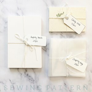 May include: Three stacks of white paper goods wrapped in twine with handwritten tags. The tags read "Catalog Cards 20pcs", "Simplicity Boards 20pcs", and "Simplicity Bags 20pcs".