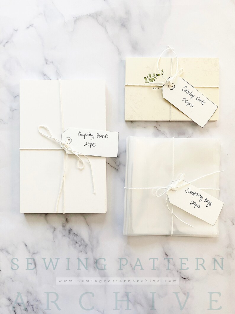 May include: Three stacks of white paper goods wrapped in twine with handwritten tags. The tags read "Catalog Cards 20pcs", "Simplicity Boards 20pcs", and "Simplicity Bags 20pcs".