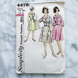 May include: Vintage Simplicity sewing pattern number 4478 for a half-size dress. The pattern includes three different styles of dresses: a yellow dress with a belt, a floral print dress, and a pink dress. The pattern is printed on white paper with black text.