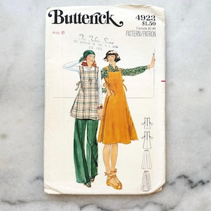 May include: Vintage sewing pattern for a dress and pants. The pattern is from Butterick and is number 4923. The pattern is for size 8 and is called "The Fabric Scene". The pattern shows two women wearing the dress and pants. The dress is a yellow sundress with a tie at the neck. The pants are green and have a wide leg.