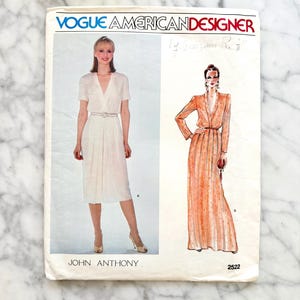 May include: Vintage Vogue American Designer sewing pattern featuring two dress designs. The pattern includes a short-sleeved dress and a long-sleeved dress with a belt. The pattern is labeled "John Anthony" and has the number 2522.