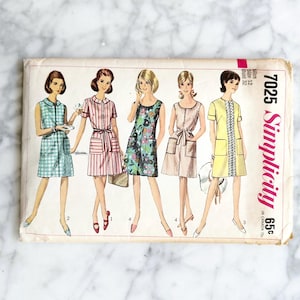 Puede incluir: Patrón de costura Simplicity vintage 7025 con cinco diseños de vestidos diferentes. Los vestidos están ilustrados en varios colores y estampados, incluyendo cuadros, rayas y estampados florales. El patrón está etiquetado con el precio y la marca.