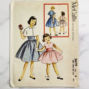 May include: Vintage McCall's sewing pattern for girls' dresses and cape. The pattern is for size 4 and costs 45 cents. The pattern shows three girls wearing different dresses and capes. The dresses are in blue, pink, and white and blue gingham.