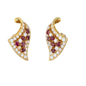 May include: A pair of gold earrings with a leaf design. The earrings are set with small diamonds and red rubies.