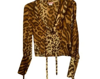 May include: A brown and beige leopard print blouse with long sleeves and a lace-up front. The blouse has a cropped fit and a V-neck.