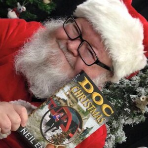 May include: Santa Claus wearing a red suit and white beard holds a book titled "Doc Christmas" by Neil Enoch.