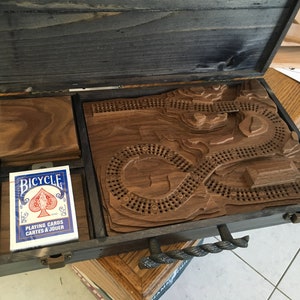 Op de afbeelding: Een houten spelbord met een gegraveerd parcours, een deck Bicycle speelkaarten en een houten doos met een touwgreep.