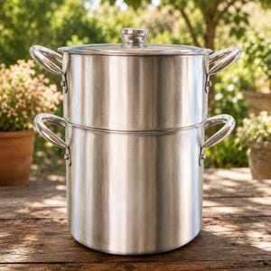Può includere: Una vaporiera in acciaio inossidabile a due livelli con coperchio abbinato. L'utensile da cucina cilindrico presenta due manici laterali su ogni sezione, una finitura metallica lucida e un design verticale impilabile.