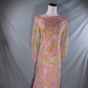 May include: A long pink and green patterned dress with long sleeves and a ruffled hem.