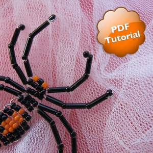 Puede incluir: Araña de cuentas negras y naranjas con una etiqueta de tutorial PDF.