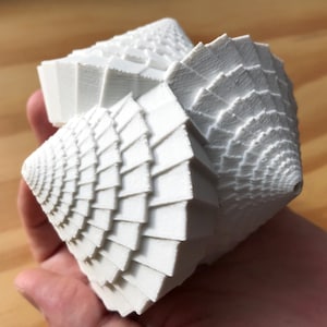 Könnte beinhalten: Eine weiße, dreidimensional gedruckte geometrische Skulptur mit einem Spiraldesign. Die Skulptur besteht aus vielen kleinen, sich überlappenden Schichten.