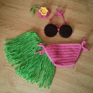 May include: A green crochet hula skirt with brown and black crochet bikini top and a yellow flower headband.