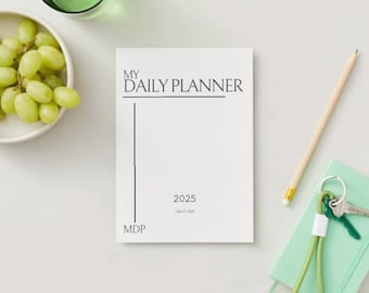 May include: A white daily planner with the text "MY DAILY PLANNER" at the top and "2025" at the bottom. The planner has a black vertical line and the text "MDP" at the bottom left corner.
