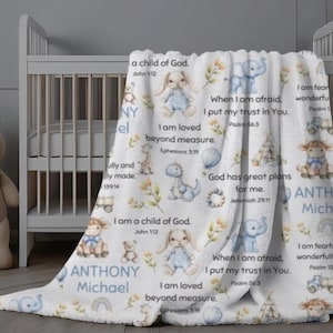 May include: A white baby blanket with a soft, plush texture. The blanket features illustrations of animals, rainbows, and text. The text includes Bible verses and the name "Anthony Michael". The blanket is draped over a white crib.