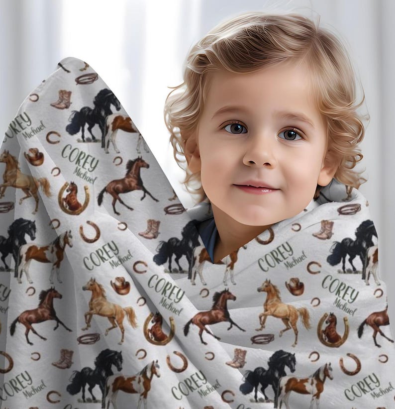 Pu&ograve; includere: Una coperta bianca a tema cavallo, con illustrazioni di cavalli marroni, neri e beige. La coperta include anche stivali da cowboy, ferri di cavallo e il nome "Corey Michael" ripetuto.