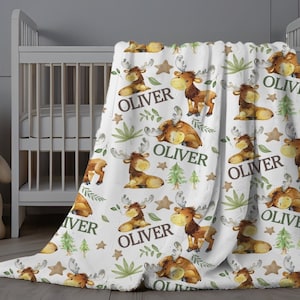 May include: White baby blanket with a repeating pattern of brown moose, green leaves, and brown stars. The blanket has the name "Oliver" printed on it multiple times.