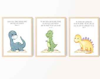 May include: Three printable wall art prints featuring cute cartoon dinosaurs with inspirational bible verses. The first print features a blue dinosaur with the verse "I can do all things through Christ who gives me strength." The second print features a green dinosaur with the verse "The child grew and became strong, he was filled with wisdom and the grace of God was on him." The third print features a yellow dinosaur with the verse "Be strong and courageous, do not be afraid, for the Lord God will be with you wherever you go."