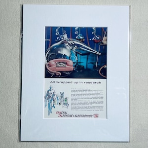 May include: A vintage advertisement print featuring a pink telephone encased in a clear glass laboratory flask. The text reads All wrapped up in research and General Telephone & Electronics, accompanied by a line drawing of a technician.