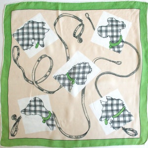 May include: A beige square scarf with a green border features a repeating pattern of black and white plaid dogs with green collars and leashes.