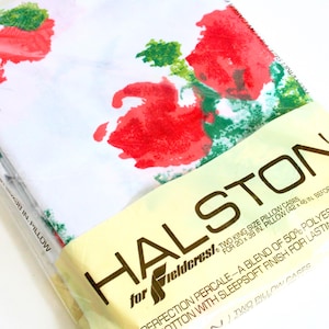 May include: A package of two king-size pillowcases with a floral pattern of red and green flowers on a white background. The package is labeled "HALSTON" and "Fieldcrest."
