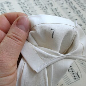 May include: White leather gloves with a number 7 written on the inside of the glove.