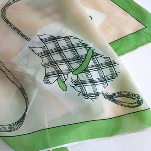 May include: A white silk scarf with a green border and a black and white plaid design of a horse's head with a bridle.