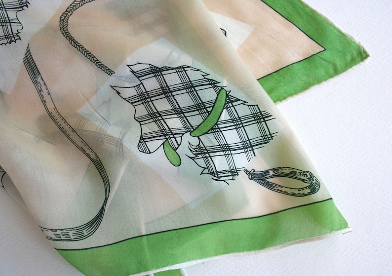 May include: A white silk scarf with a green border and a black and white plaid design of a horse's head with a bridle.