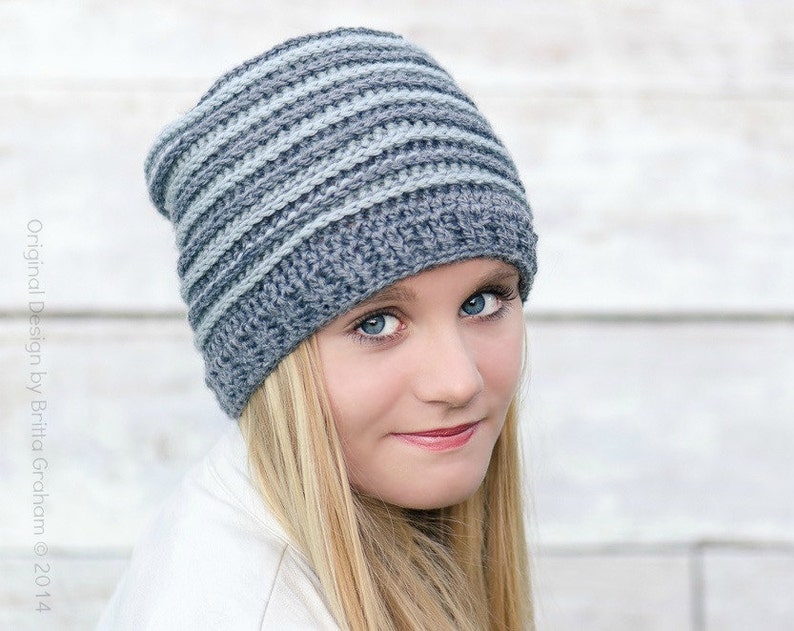 May include: A gray and light blue striped crochet beanie hat. The hat is made with a soft yarn and has a slouchy fit.