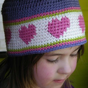 May include: A purple crocheted hat with a white and pink heart design and green and pink stripes.