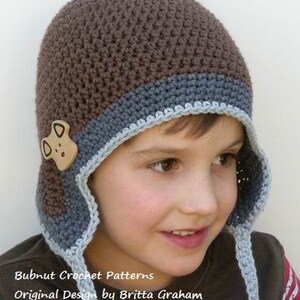 May include: A brown and blue crocheted hat with a brown felt dog applique. The hat has a long, blue crocheted tie. Bubnut Crochet Patterns Original Design by Britta Graham Copyright &copy; 2011