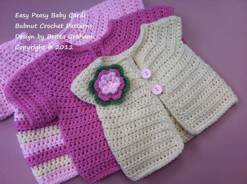 May include: Three crocheted baby cardigans in pink, cream, and striped pink and cream. The cream cardigan has a flower embellishment and two pink buttons. The text "Easy Peasy Baby Cardi Bubnut Crochet Patterns Design by Britta Graham Copyright @ 2012" is visible in the image.