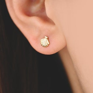 Op de afbeelding: Een paar gouden schelp oorbelletjes. De oorbelletjes zijn klein en delicaat, en perfect om een vleugje speelsheid toe te voegen aan elke outfit.