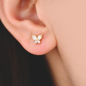 May include: A pair of gold butterfly earrings with clear cubic zirconia stones.