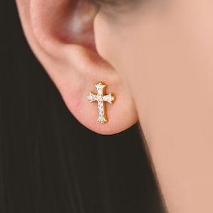 May include: A pair of gold cross earrings with small clear cubic zirconia stones.