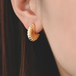 Puede incluir: Un par de pendientes de aro de oro con un diseño texturizado en forma de abanico.